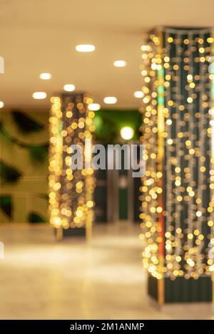 Die Einkaufshalle ist für Weihnachten unscharf dekoriert. Weihnachtseinkäufe verschwommener Hintergrund. Stockfoto