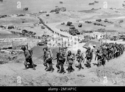 OMAHA BEACH, NORMANDIE, FRANKREICH - 07. Juni 1944 - Truppen der US Army 2. Infanterie Division marschieren beim E-1-Draw im Easy Red Sektor hoch Stockfoto