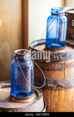 Ein vertikales Bild von altblauen Glasbehältern auf Holzfässern Stockfoto