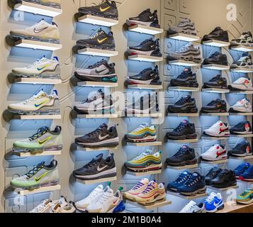 Schau dir viele Sportschuhe an der Wand an. Ein Blick auf eine Schuhwand im Nike Shop vor Ort. Moderne neue, stylische Laufschuhe für Sneaker für m Stockfoto