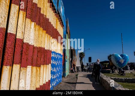 San Diego, USA. 10.. Dezember 2022. Die Grenzmauer zwischen Mexiko und den Vereinigten Staaten ist mit Wandgemälden auf der Tijuana-Seite des Zauns bedeckt. Dieses Wandgemälde zeigt eine umgedrehte amerikanische Flagge, ein Symbol der Not aus einem bestimmten Blickwinkel und listet die Namen von Migranten auf, die bei der Überquerung der Grenze von einem anderen Ort ums Leben gekommen sind. Tijuana, 10. Dezember 2022. (Matthew Bowler/KPBS/Sipa USA) **KEIN VERKAUF IN SAN DIEGO-SAN DIEGO OUT** Guthaben: SIPA USA/Alamy Live News Stockfoto