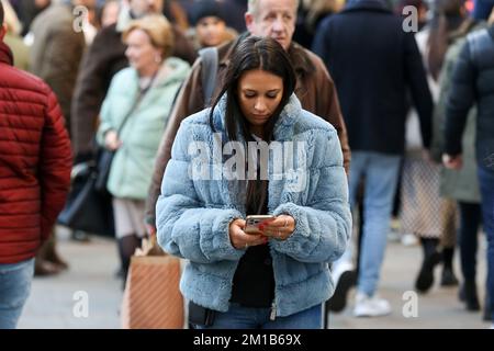 London, Großbritannien. 10.. Dezember 2022. Eine Frau benutzt ihr Handy, während sie in der Oxford Street im Zentrum Londons spaziert. (Foto: Dinendra Haria /SOPA Images/Sipa USA) Guthaben: SIPA USA/Alamy Live News Stockfoto