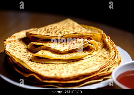 Heiße, frisch gebackene Pfannkuchen mit Marmelade. Hausgemachte Rosehip ( rosa canina ) Marmelade in weißer Keramikschüssel. Makrofotografie von Pfannkuchen. Nahaufnahme von Pa Stockfoto