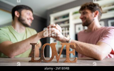 Zwei Männer schütteln sich die Hand mit der Vordergrundschrift Liebe Stockfoto