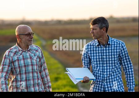 Porträt zweier reifer Bauern, die im Herbst bei Sonnenuntergang auf dem Feld stehen Stockfoto