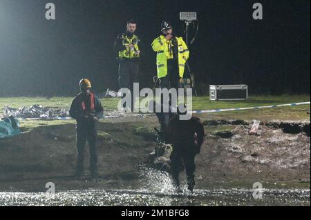 Babbs Mill Park, Solihull, 11.. Dezember 2022. Ein Offizier betritt den See mit einer spezialisierten Unterwasserdrohne, bevor Taucher von der Nottinghamshire Polizei eintreffen und durchsuchen Babbs Mill Lake nach 2 Menschen, die immer noch vermisst werden, nachdem 4 andere gerettet wurden, nachdem sie Sonntagabend durch das dünne Eis gefallen sind. Der Taucher tauchte regelmäßig mit grünem Unkraut auf, was die schwierigen Arbeitsbedingungen verdeutlicht. Die Polizei in West Midlands hatte zuvor eine Unterwasserdrohne benutzt, um die Vermissten zu lokalisieren. Feuerwehr und Rettungsdienst mit spezialisierten Wasserrettungsteams sind immer noch am Tatort in der Nähe von Fordbridge Stockfoto