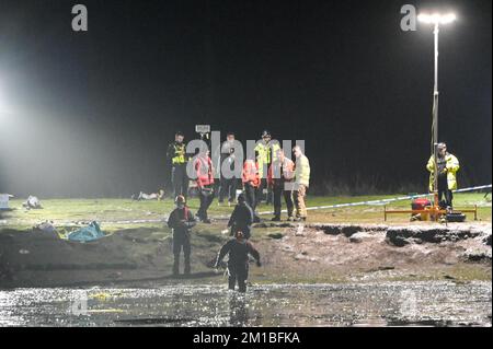 Babbs Mill Park, Solihull, 11. Dezember 2022. Taucher von der Nottinghamshire Police sind angekommen und suchen den Babbs Mill Lake nach 2 Personen, die immer noch vermisst werden, nachdem 4 andere gerettet wurden, nachdem sie am Sonntagabend durch das dünne Eis gefallen waren. Der Taucher tauchte regelmäßig mit grünem Unkraut bedeckt auf, was die schwierigen Arbeitsbedingungen veranschaulicht. Die West Midlands Police hatte früher eine Unterwasserdrohne benutzt, um die Vermissten zu lokalisieren. Feuerwehr und Krankenwagen mit spezialisierten Wasserrettungsteams sind immer noch am Einsatzort in der Nähe der Fordbridge Road, Kingshurst, Solihull England. Quelle: Stop Press Media/Alamy L Stockfoto