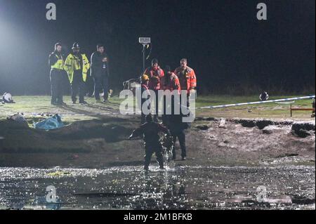 Babbs Mill Park, Solihull, 11.. Dezember 2022. Die Polizei holt eine Unterwasserdrohne aus dem eisigen Wasser, als Taucher von der Nottinghamshire Polizei eintreffen und Babbs Mill Lake nach 2 Menschen durchsuchen, die noch vermisst werden, nachdem 4 andere gerettet wurden, nachdem sie Sonntagabend durch das dünne Eis gefallen sind. Der Taucher tauchte regelmäßig mit grünem Unkraut auf, was die schwierigen Arbeitsbedingungen verdeutlicht. Die Polizei in West Midlands hatte zuvor eine Unterwasserdrohne benutzt, um die Vermissten zu lokalisieren. Feuerwehr und Rettungsdienst mit spezialisierten Wasserrettungsteams sind immer noch am Tatort nahe Fordbridge Road, King Stockfoto