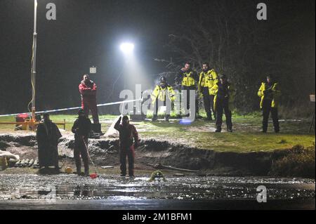 Babbs Mill Park, Solihull, 11. Dezember 2022. Taucher von der Nottinghamshire Police sind angekommen und suchen den Babbs Mill Lake nach 2 Personen, die immer noch vermisst werden, nachdem 4 andere gerettet wurden, nachdem sie am Sonntagabend durch das dünne Eis gefallen waren. Der Taucher tauchte regelmäßig mit grünem Unkraut bedeckt auf, was die schwierigen Arbeitsbedingungen veranschaulicht. Die West Midlands Police hatte früher eine Unterwasserdrohne benutzt, um die Vermissten zu lokalisieren. Feuerwehr und Krankenwagen mit spezialisierten Wasserrettungsteams sind immer noch am Einsatzort in der Nähe der Fordbridge Road, Kingshurst, Solihull England. Quelle: Stop Press Media/Alamy L Stockfoto