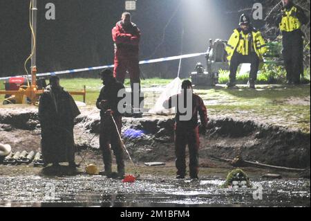 Babbs Mill Park, Solihull, 11. Dezember 2022. Taucher von der Nottinghamshire Police sind angekommen und suchen den Babbs Mill Lake nach 2 Personen, die immer noch vermisst werden, nachdem 4 andere gerettet wurden, nachdem sie am Sonntagabend durch das dünne Eis gefallen waren. Der Taucher tauchte regelmäßig mit grünem Unkraut bedeckt auf, was die schwierigen Arbeitsbedingungen veranschaulicht. Die West Midlands Police hatte früher eine Unterwasserdrohne benutzt, um die Vermissten zu lokalisieren. Feuerwehr und Krankenwagen mit spezialisierten Wasserrettungsteams sind immer noch am Einsatzort in der Nähe der Fordbridge Road, Kingshurst, Solihull England. Quelle: Stop Press Media/Alamy L Stockfoto