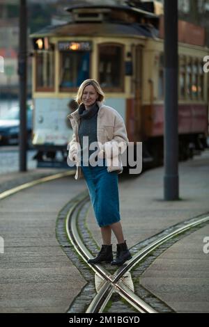 Eine Frau, die in der Nähe einer alten Straßenbahn steht. Stockfoto