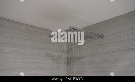 Aus dem rostfreien Duschkopf im Badezimmer fließendes Wasser Stockfoto