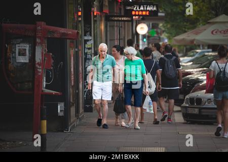 Bild einer Gruppe von zwei älteren Personen in Belgrad, Serbien, die schwere, hauptsächlich Lebensmittel enthaltende Lebensmittelbeutel auf dem Rückweg vom Su mit sich herumtragen Stockfoto