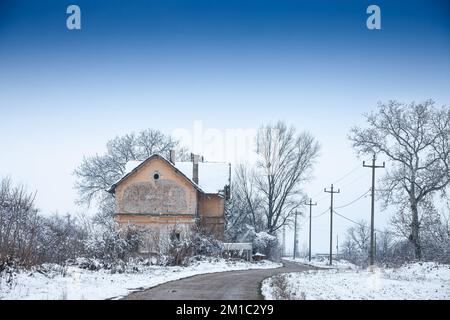 Foto des Bahnhofs in Bavaniste, Serbien, aufgenommen während eines kalten, sonnigen Winternachmittags, gefroren, mit Schnee bedeckt, inmitten von Bäumen Stockfoto