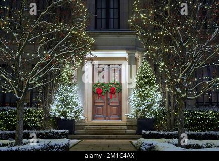 Vorgarten des Hauses mit dekorativen Weihnachtslichtern an Bäumen im Winter Stockfoto