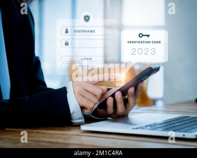Zwei-Stufen-Authentifizierung (2FA) Konzept. 2023, Bestätigungscode und Schlüsselsymbol auf dem Smartphone während der Verwendung des Computers zur Passwortbestätigung, IDE Stockfoto