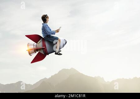 Kind trägt Kopfhörer auf einer Rakete Stockfoto