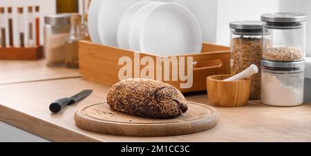 Schneidebrett mit frischem Brot und Messer auf der Theke in der Küche Stockfoto