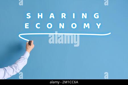 Ein Geschäftsmann, der auf einem virtuellen Bildschirm vor blauem Hintergrund schreibt. Konzept der Sharing Economy Stockfoto