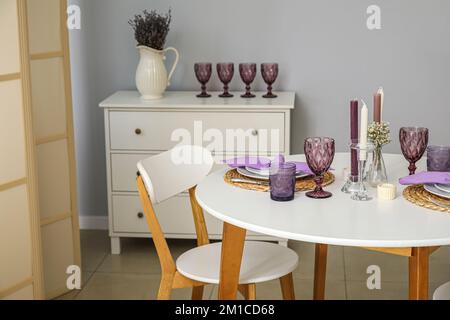 Wunderschöne Umgebung, Kerzen und Zigeunerblumen auf einem weißen Tisch in einem hellen Raum Stockfoto