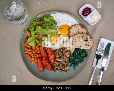 Großes amerikanisches Frühstück mit zwei Eiern, Pilzen, Bohnen, Würstchen. Stockfoto