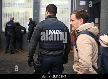 PRODUKTION - 29. November 2022, Hessen, Frankfurt/Main: Polizeikommissar Niklas Möller (r), vor-Ort-Schutzbeauftragter, steht am Rande einer Hintergrundüberprüfung, die von seinen Kollegen vom 4.. Bezirk im Bahnhofsviertel durchgeführt wird. Seit mehr als einem Jahr ist er Ansprechpartner für Institutionen, Handwerker und Bürger des Bezirks, einem Hotspot in der Hauptmetropole. Mit seinen Touren stärkt er die Sicherheit in der Nachbarschaft. (Nach dpa-Korr 'zwischen Wochenmarkt und Bordell - Wachmann im Bahnhofsviertel') Foto: Arne Dedert/dpa Stockfoto