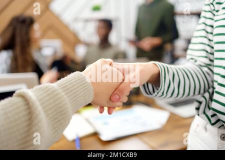 Geschäftsfrauen, die sich in einem Co-working-Center die Hand schütteln. Stockfoto