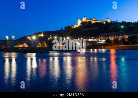 Das beleuchtete Schloss „Festung Marienberg“ befindet sich auf einem Hügel über der Stadt, der Brücke „Alte Mainbrücke“ über dem Main, die bei Nacht zu sehen ist Stockfoto