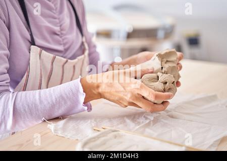 Die unbekannte Töpfermeisterin, die in ihrem Keramikstudio einen Stapel Lehm für die Herstellung eines Töpfchens auf dem Töpferrad vorbereitet. Hochwertiges Foto Stockfoto