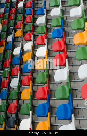 Eine Gruppe von farbenfrohen Plastikstühlen in einem Fußballstadion Stockfoto
