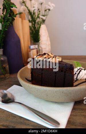 Nahaufnahme: Schokoladen-Fudge-Brownie, garniert mit Mandelscheiben in einer Keramikschüssel Stockfoto