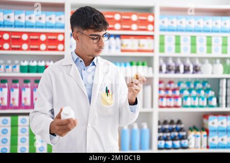 Junger hispanic-Mann Apotheker hält Pillen Flaschen in der Apotheke Stockfoto