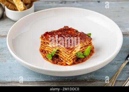 Béchamelsauce und Lasagne mit Hackfleisch auf einem Holztisch Stockfoto