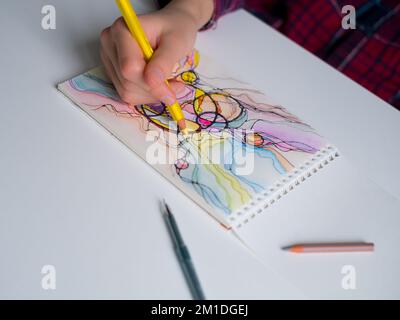 Abstraktes neurographisches Zeichnen mit Stift und Buntstiften. Nahaufnahme von Händen, die neurographische Kunst zeichnen. Neurographische Kunst - eine moderne Methode der Kunst Stockfoto