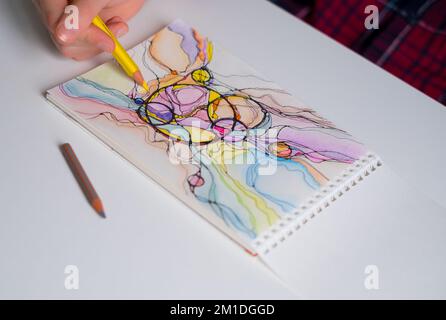 Abstraktes neurographisches Zeichnen mit Stift und Buntstiften. Nahaufnahme von Händen, die neurographische Kunst zeichnen. Neurographische Kunst - eine moderne Methode der Kunst Stockfoto