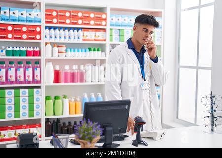 Junger hispanischer Apotheker, der in der Apotheke telefoniert Stockfoto