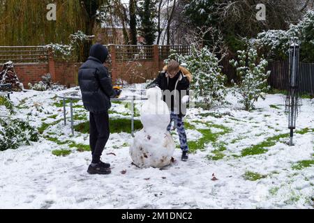 Hamstreet, Kent, Großbritannien. 12.. Dezember 2022. UK Weather: Das Dorf Hamstreet in der Nähe von Ashford in Kent wacht mit einem Schneestaub auf. Teenager, die wegen des Schnees nicht zur Schule gehen, machen einen Schneemann im Garten. Foto: Paul Lawrenson/Alamy Live News Stockfoto