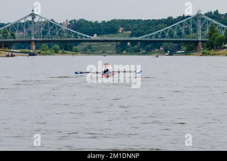 Zwei Mädchen rudern ein Sportruderboot auf der Elbe. Die Brücke 'Blaues Wunder' in der Ferne Stockfoto