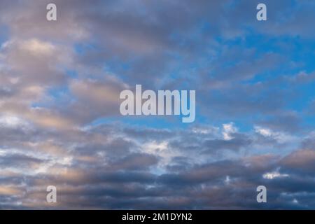 Wunderschöner Sonnenuntergang- oder Sonnenaufgangshimmel, der dunkelblaue und blassrosa Wolken erhellt. Wolkiger Himmel, um auf Ihren Fotos zu überlagern. Stockfoto