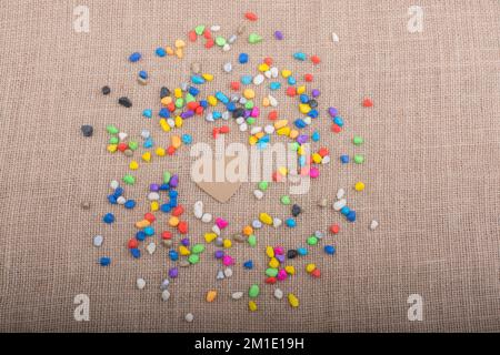 Herz aus Papier inmitten der bunten Steinchen auf Leinwand Boden Stockfoto