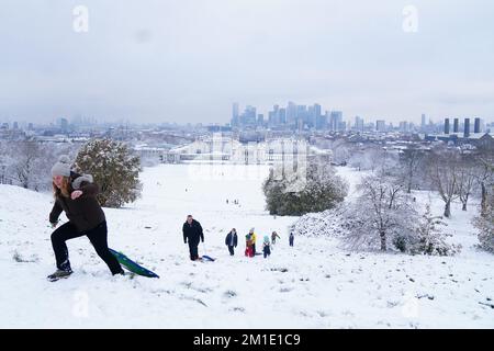 Leute, die im Snow Greenwich Park in London schlittenfahren. Schnee und Eis haben sich über Teile Großbritanniens ausgebreitet, und die kalten Winterbedingungen werden tagelang anhalten. Foto: Montag, 12. Dezember 2022. Stockfoto