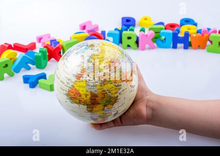 Kleines Modell gobe in Hand mit bunten Buchstaben hinter Stockfoto