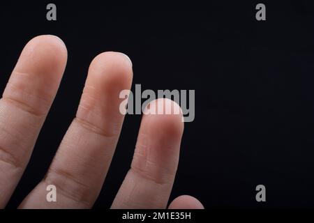Drei Finger einer Hand des Kindes teilweise in schwarzen Hintergrund gesehen Stockfoto