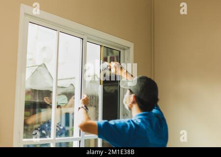 Arbeiter verwenden Schaber-Reinigungsfenster, bevor sie Abfärbefolien anbringen. Stockfoto