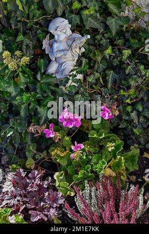 Grab mit Blumendekoration und Putto mit Geige auf dem Friedhof der Kirche St. Blasius in Diepolz, Allgäu, Bayern, Deutschland, Europa Stockfoto