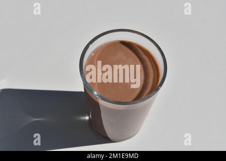 Isoliertes Glas der frischen Schokoladenmilch auf der weißen Oberfläche Stockfoto