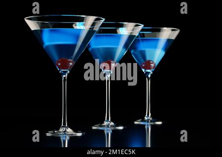 Drei blaue Cocktails mit Kirsche auf schwarzem Hintergrund Stockfoto