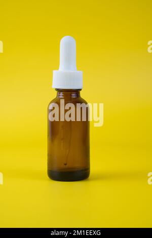 Medizinische braune Glas Tropfflasche leer isoliert vor gelbem Hintergrund Stockfoto