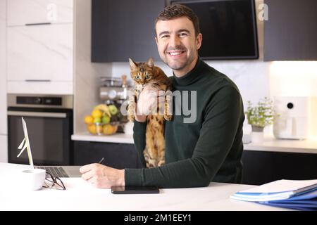 Attraktiver Mann, der mit seiner Katze von zu Hause aus arbeitet Stockfoto