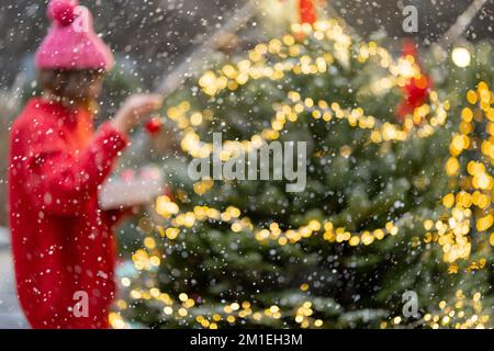 Die Frau schmückt den Weihnachtsbaum auf dem Schrottplatz, verschwommenes Bild Stockfoto